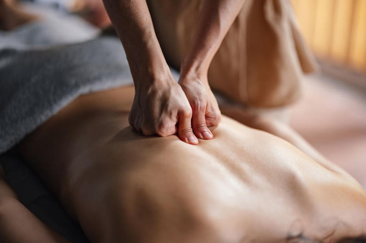 Deep tissue massage — firm focused pressure with both hands on the upper back